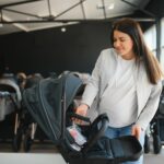 Young pregnant woman in shop of children goods. The choice for a baby stroller