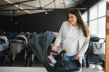 Young pregnant woman in shop of children goods. The choice for a baby stroller
